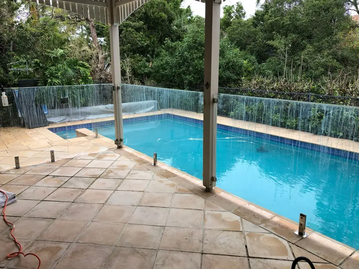 Heavily mineral-stained pool fence glass before restoration